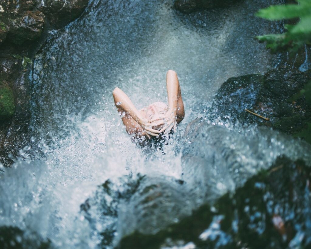 femme qui se douche sous une cascade